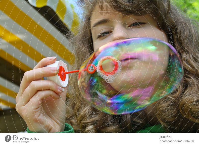Girl blows big soap bubble Young woman Soap bubble variegated Happiness Ease Free Cheerful Exterior shot Summer Joy Day Dream Playing free time