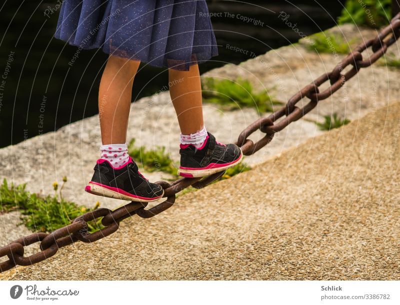 Young girl balancing over a heavy iron chain Girl Legs Skirt young girl Iron chain balance Diagonal Shallow depth of field Copy Space bottom Copy Space right