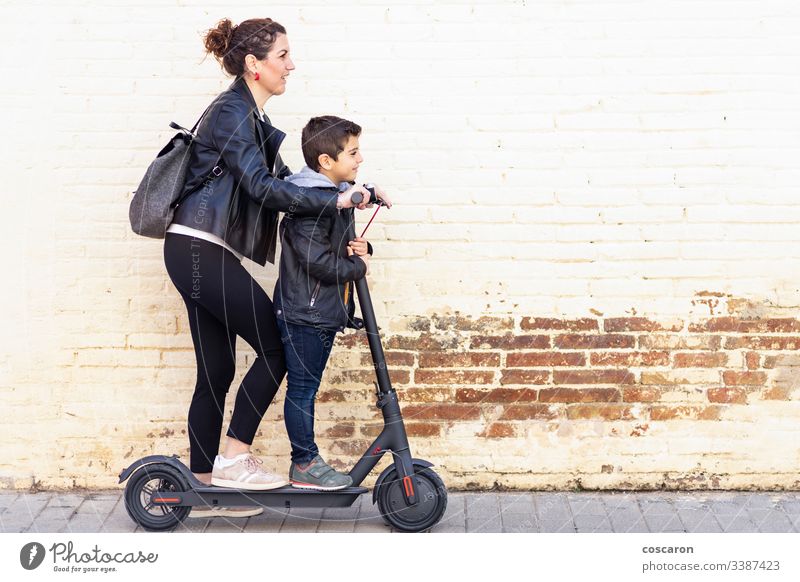 Mother and son riding an electric scooter active boy casual child city day e-scooter eco europe family female fun generation kick kick scooter leisure lifestyle