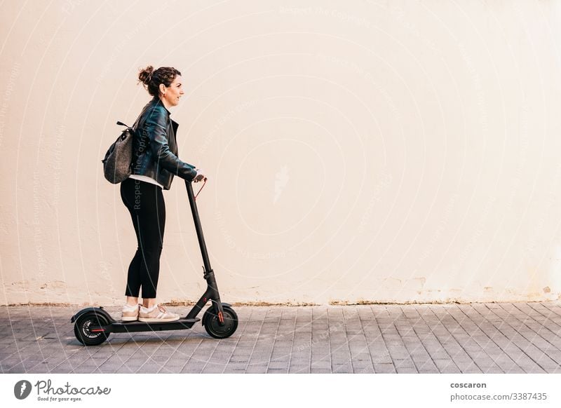 Middle aged woman riding an electric scooter active adult alone attractive background board business cheerful city driving e scooter eco electrical equipment