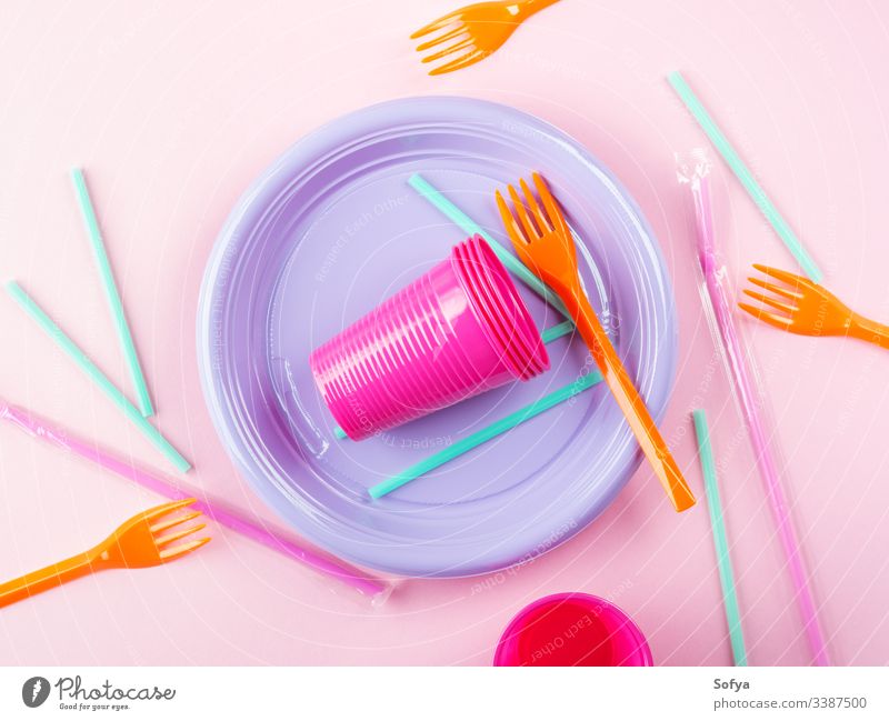 Disposable colorful plastic dish, straws and cups, cutlery. Flat lay on pink background. disposable tableware plate ban pollution throw flat lay stop garbage