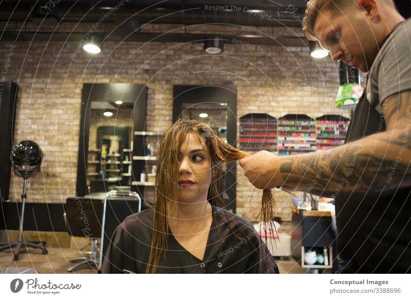 Caucasian woman having her hair styled in a hipster barbershop themes of hairstylist pampering glamour haircare haircut salon hairdressing hairdresser hairstyle