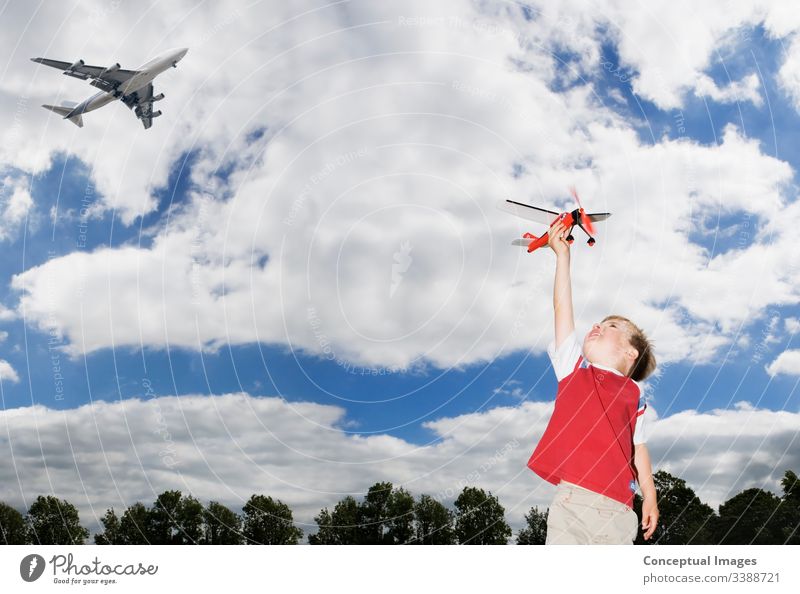 Young boy playing with a toy planeYoung caucasian boy playing with a toy plane as a passenger plane flies overhead themes of future imagination inspiration