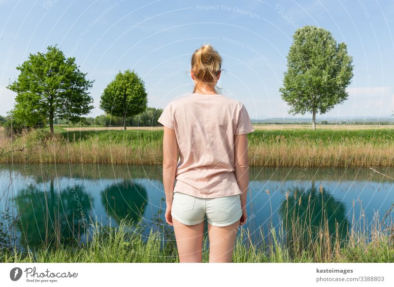 Young woman wearing casual summer clothes enjoying beautiful view of peaceful countryside. nature meadow rear young beauty day green healthy field girl adult