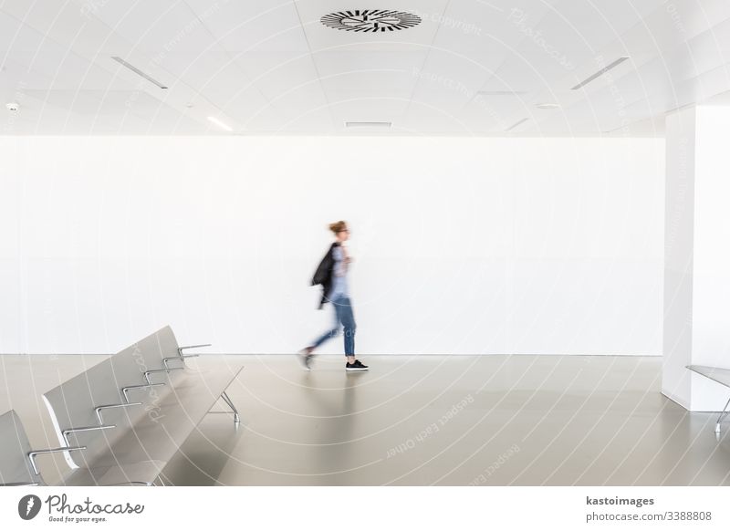 Motion blur of woman walking at contemporary white empty hallway interior architecture motion seats terminal modern room caucasian female blurred health light