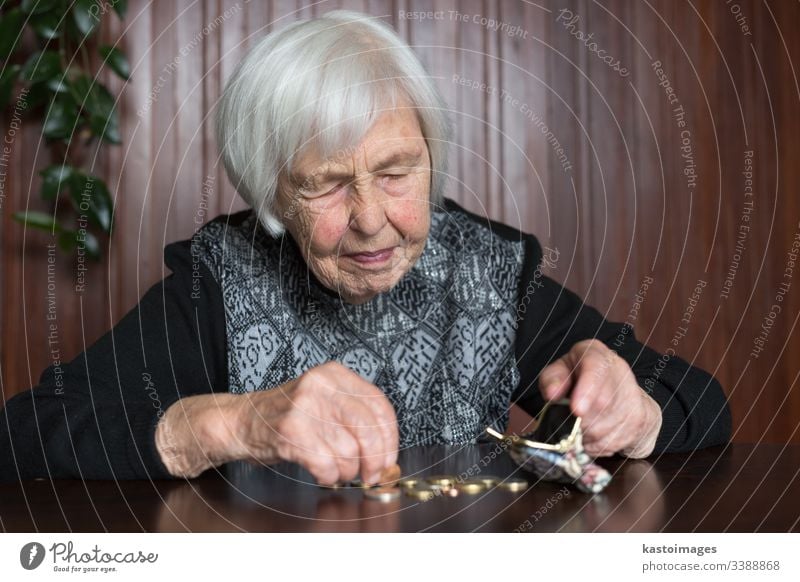 Elderly woman sitting at the table counting money in her wallet. senior pensioner elderly poverty retirement old empty coins background miserable broke lonely
