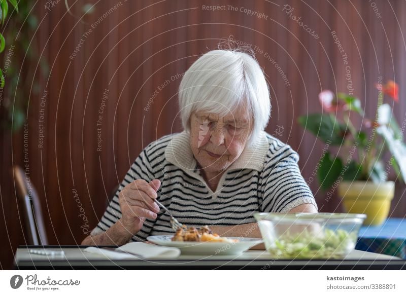 Solitary senior woman eating her lunch at retirement home. pensioner elderly wallet poverty old retired grandmother person dining dinner meal caucasian food