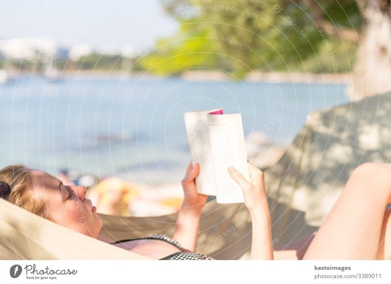Woman reading book in hammock on the beach vacation day female woman relax young novel relaxation rest summer leisure lying human idyllic person resort relaxing