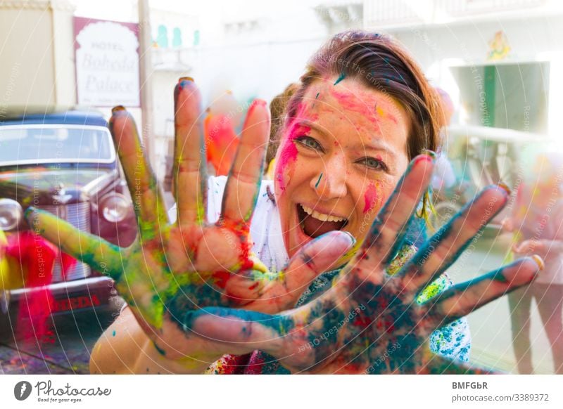 woman having fun at holi festival showing her coloured hands in the camera excited crazy enjoying festival of colours tourism concept happiness summer holy