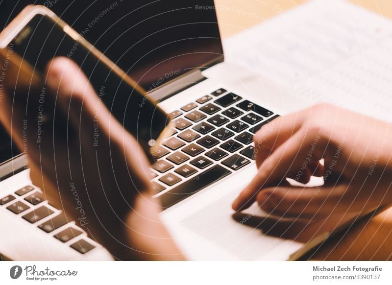 Woman working on notebook and holding phone in other hand technology screen mobile computer business laptop internet communication using smart person display