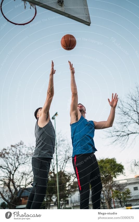 Two young friends playing basketball. game youth sport court male team together active action playground exercise men friendship jump happy athlete fitness