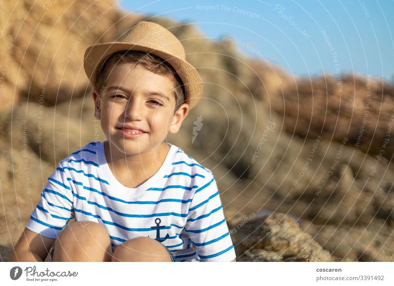 Portrait of a cute child sitting on a rocks near the sea anchor baby background beach beautiful blond blue boy bright caucasian childhood coast eyes fun