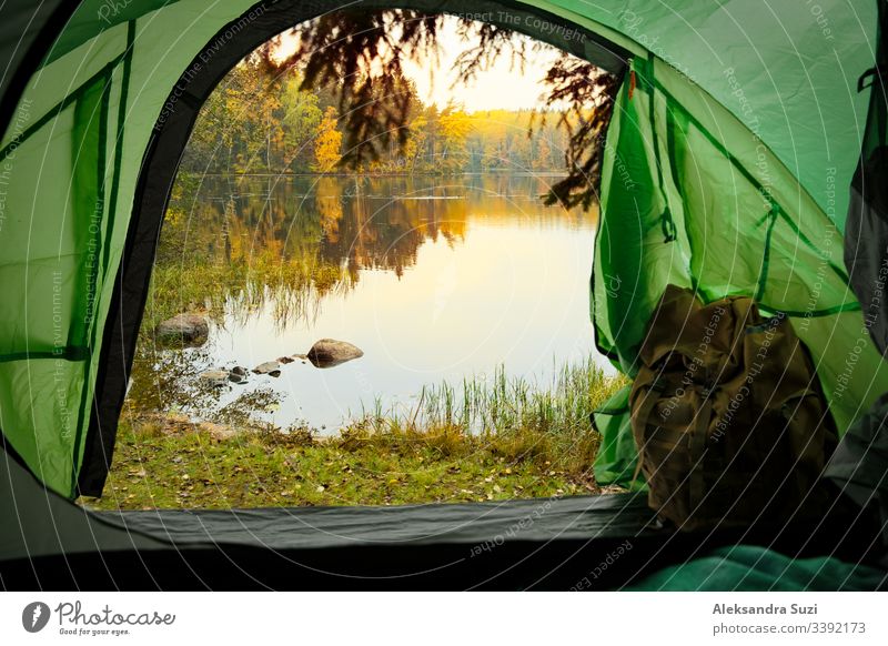 View from inside a tourist tent with backpack. Beautiful Scandinavian landscape of forest and lake. Finland active activity adventure autumn beautiful camp