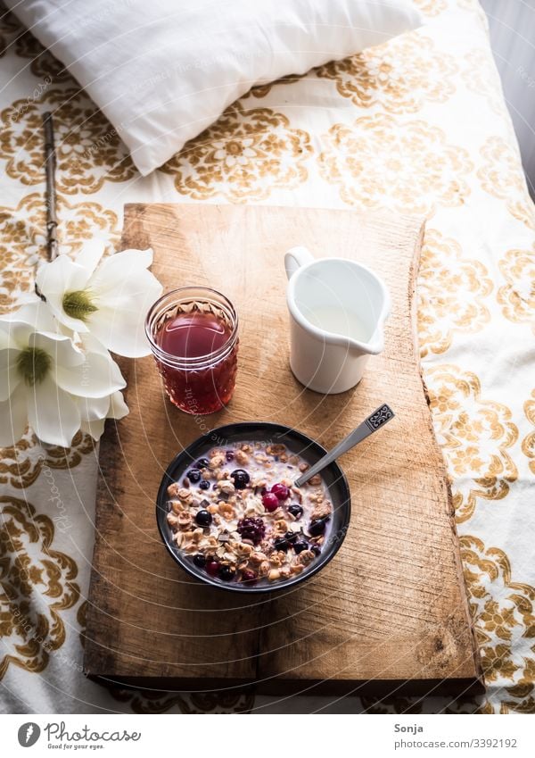 Romantic breakfast with muesli, milk and fresh berries on a wooden serving tray in bed Breakfast Milk raspberry blueberry Bed Retro Wooden board Spoon