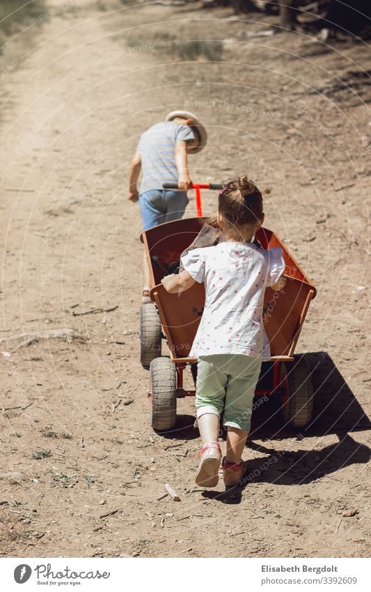Little boy and little girl pushing a handcart Handcart vacation Summer children Girl Boy (child) sunshine Family Trip Brothers and sisters out Discover