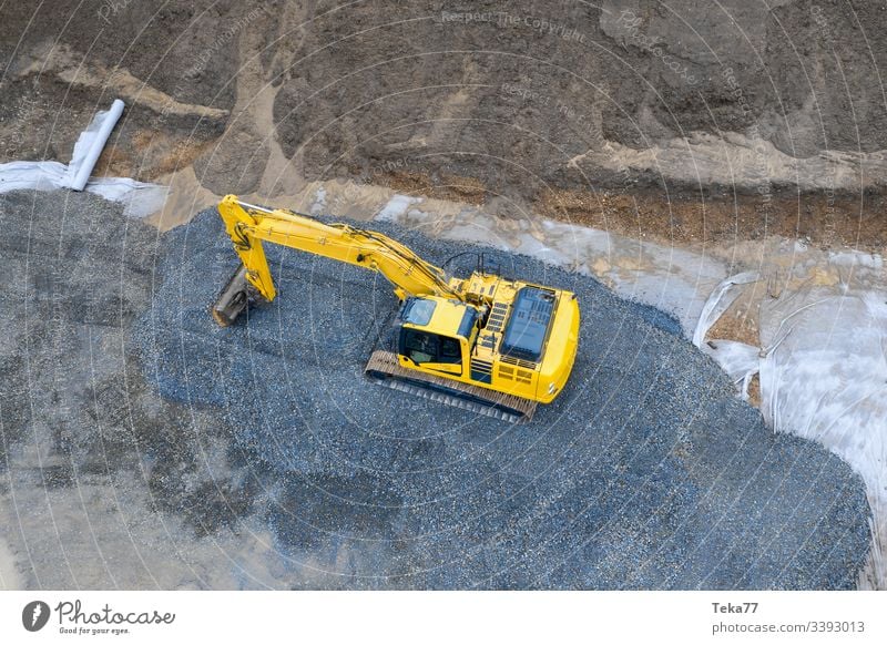 excavator on an construction site from above excavator from above yellow mud water gravel stone modern construction machine aerial view geometrical down below