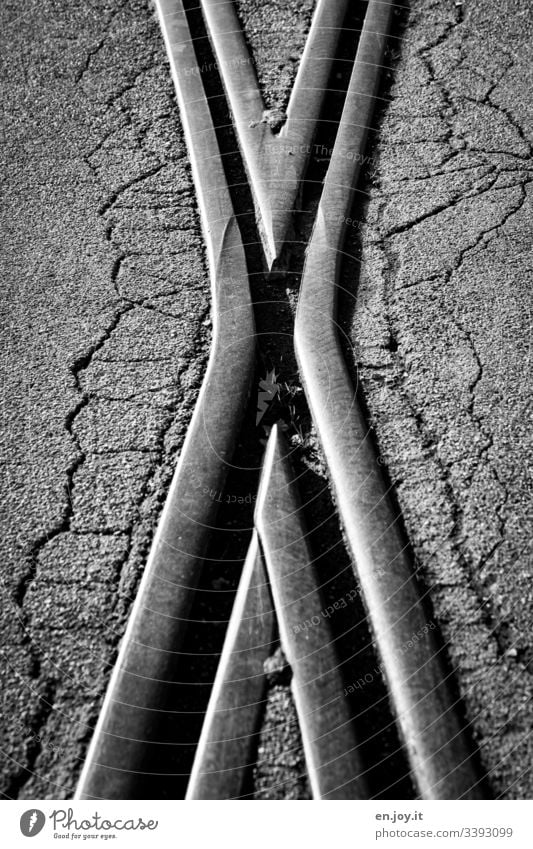 Railway tracks crossing on asphalt with cracks Railroad tracks rails railway tracks Asphalt Broken Crucifix Gray Black White Transportation
