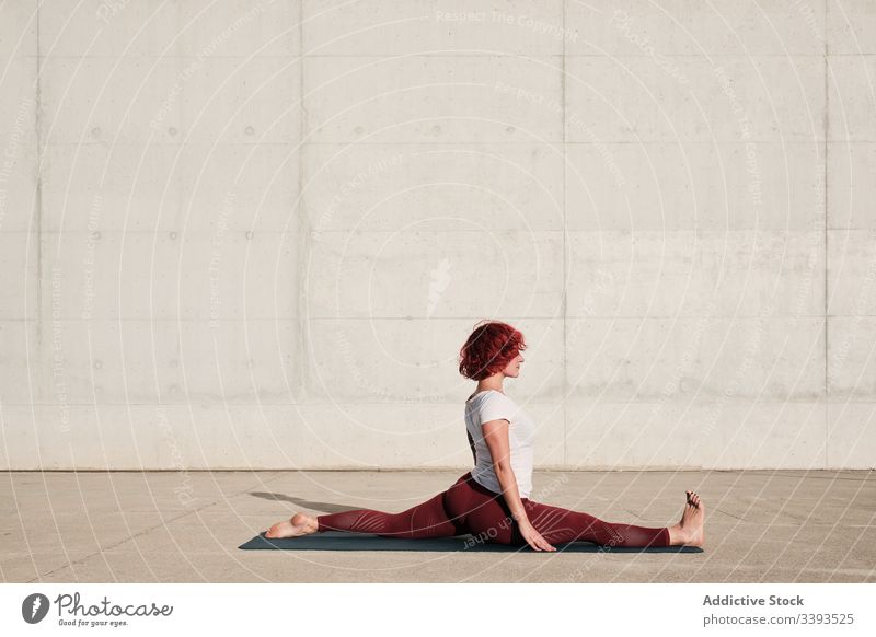 Flexible female yoga instructor with eyes closed exercising at