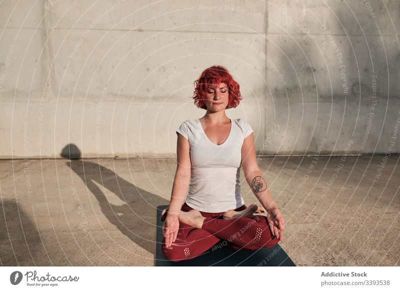 Woman with eyes closed meditating in lotus pose on street during sunset woman meditate yoga tranquil practice gyan mudra flexible idyllic gymnastic athlete