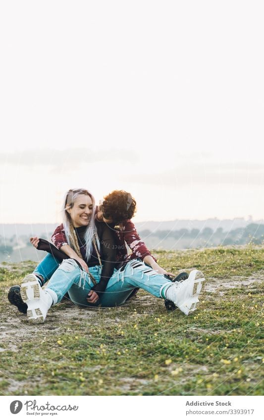 Content female teenagers hugging on grass women girlfriend laugh fun nature meadow best friend embrace smile enjoy share casual contemporary sit hipster green