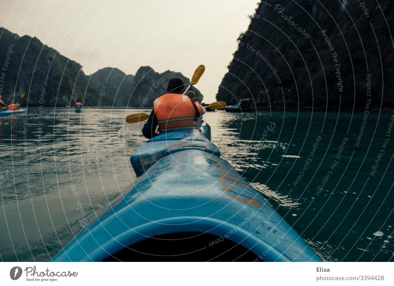 Kayaking tourists in blue kayaks with orange life jackets in Halong Bay, Vietnam Ocean Life jacket Halong bay Water Vantage point Sports Adventure Rock Nature