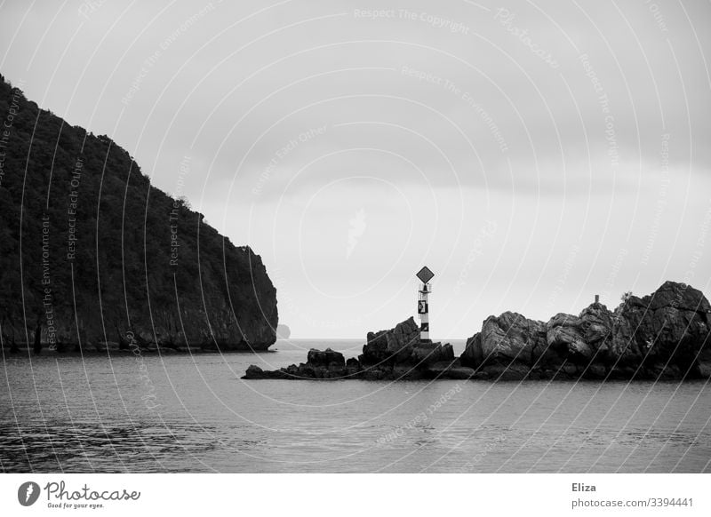 Rocks in the sea on which there is a little tower with a sign Ocean edged Landscape Halong bay Black & white photo fissured Tower Water Vietnam Nature Sky Gray