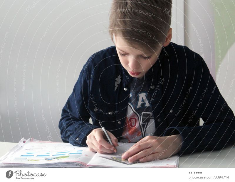 Boy does homework Boy (child) blonde hair Blonde Hair and hairstyles pen Pencil Homework Face Looking Portrait photograph Downward Write Writing