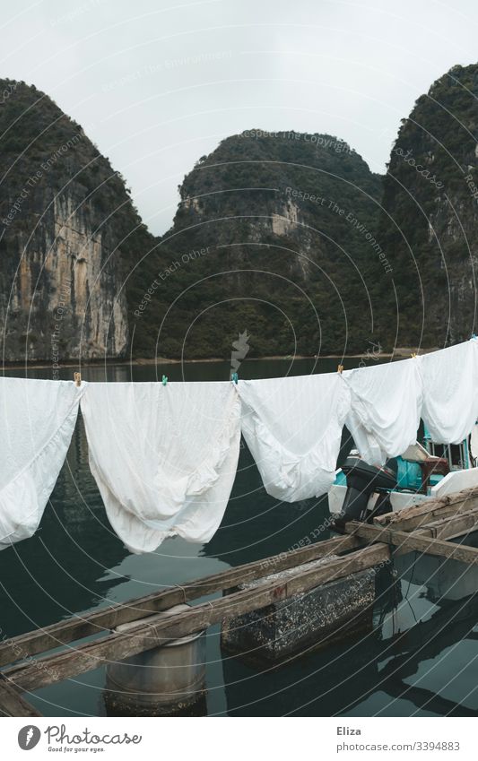 White laundry on a clothesline in a floating village in Halong Bay, Vietnam Clothesline Laundry Sheet Limestone rocks Landscape aquatic life wooden planks