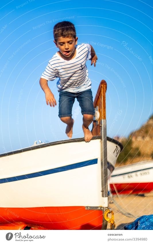 Little child jumping from a boat with a blue sky background active air beach beautiful boy carefree cheerful childhood coast coastline energy enjoy fly freedom