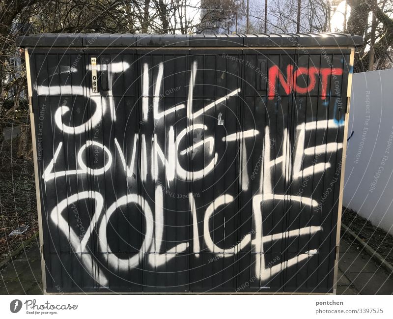 Graffiti on a power box. English r text about the aversion to the police. Police violence Police Force dislike Black Text leap words Youth culture Exterior shot