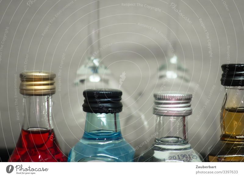 Four bottles of coloured spirits in front of two glasses Liquids Alcoholic drinks Spirits Red Blue Beverage Glass Drinking Minibar Hotel four Close-up
