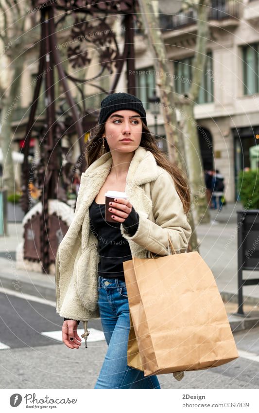 Portrait of young european woman walking in a city street, with takeaway coffee in hands modern town alone beautiful cup attractive urban downtown girl stroll
