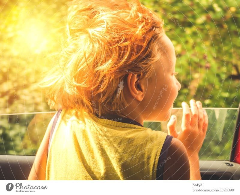 Little boy enjoying sun and wind travelling in a car little child happy skin emotion moment hair summer sunny day light t-shirt yellow blonde caucasian eyes kid