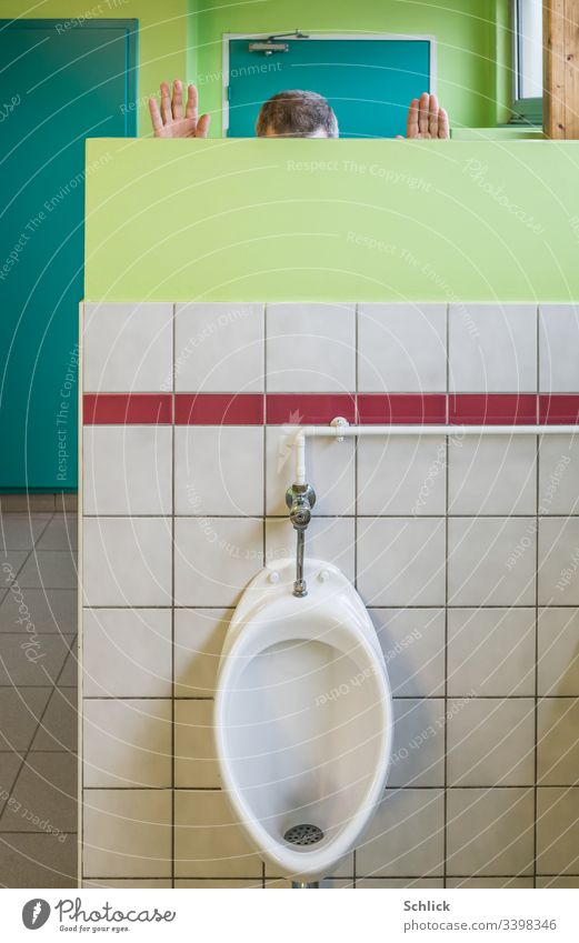 Man pees freehand behind a screen in a urinal Urinate Freehand Screening Joke Gags hair hands Head Crested tiles LAVATORY covert White Red Green Turquoise