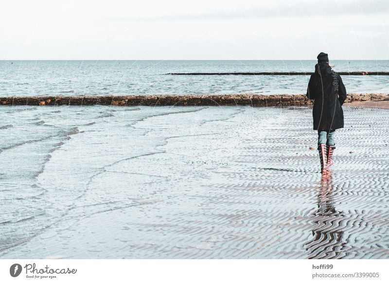 Woman with red striped rubber boots walks alone on the beach in winter Rubber boots Red red rubber boots Legs Boots North Sea coast Mud flats watt Landscape