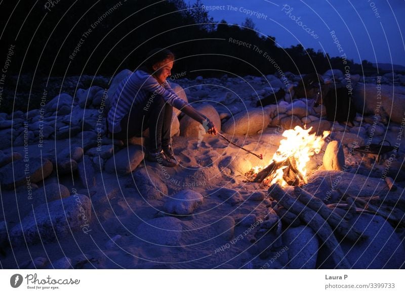 Woman holding a stick next to a camp fire in the evening young woman outside outdoors Camp fire atmosphere Fire Colour photo Exterior shot Hot Night Fireplace