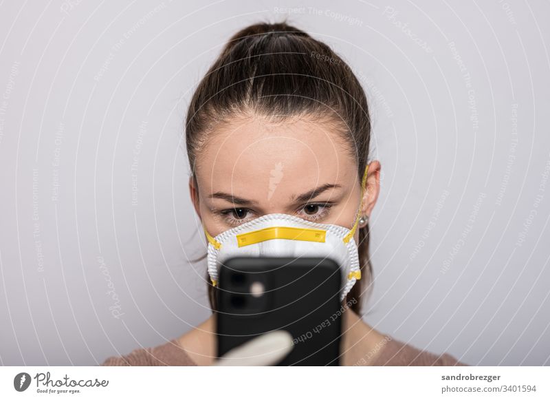 Woman with a mouthguard and disposable gloves types on her mobile coronavirus covid-19 Virus Illness pandemic Epidemic Mask guard sb./sth. hand protection