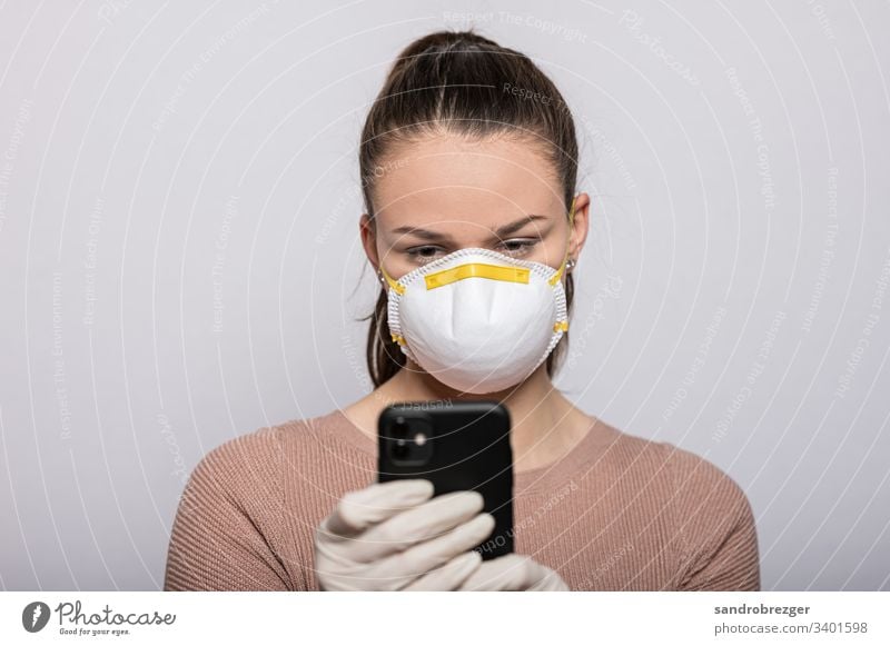 Woman with mouthguard and disposable gloves reads on smartphone coronavirus covid-19 Virus Illness pandemic Epidemic Mask guard sb./sth. hand protection Sterile