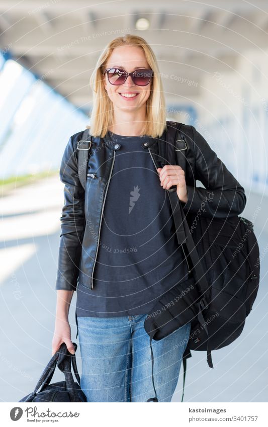 Portrait of young cheerful female traveler wearing casual clothes carrying heavy backpack and luggage at airport. woman baggage trip adventure tourist lady girl