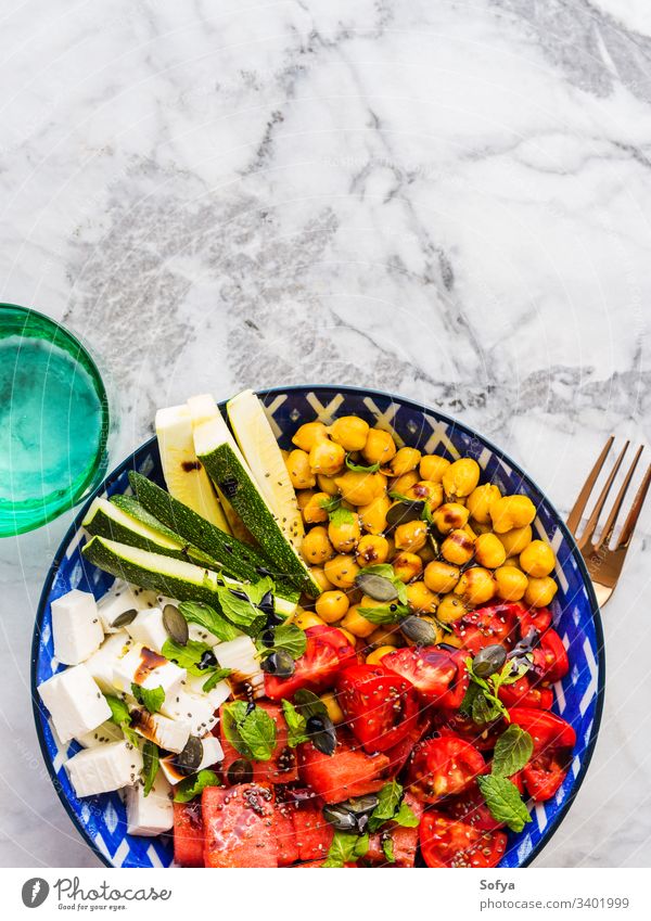 Chickpea watermelon salad with feta and tomatoes, zucchini and pumpkin seeds food colorful turmeric chickpea cheese top view flat lay mint balsamic vinegar
