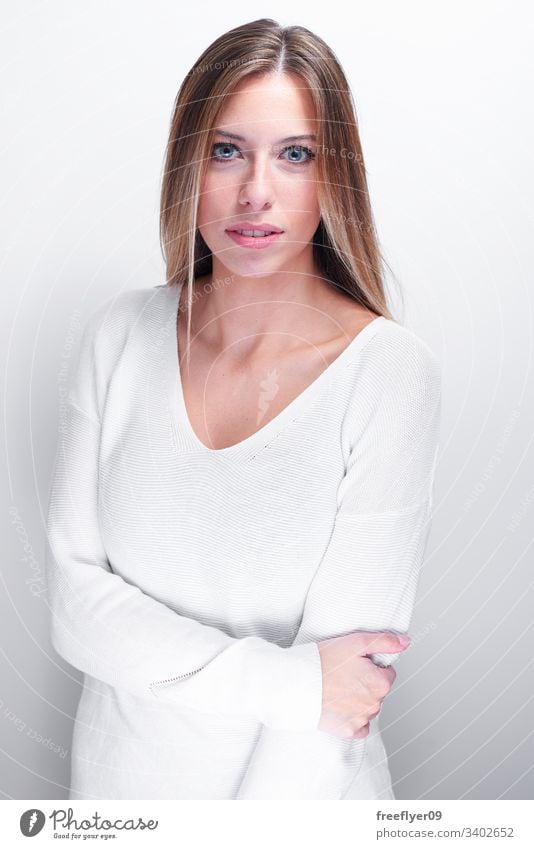 Shy woman looking at camera on a white background long haired blonde female high key blue eyes clear eyes portrait vertical happy girl european young caucasian