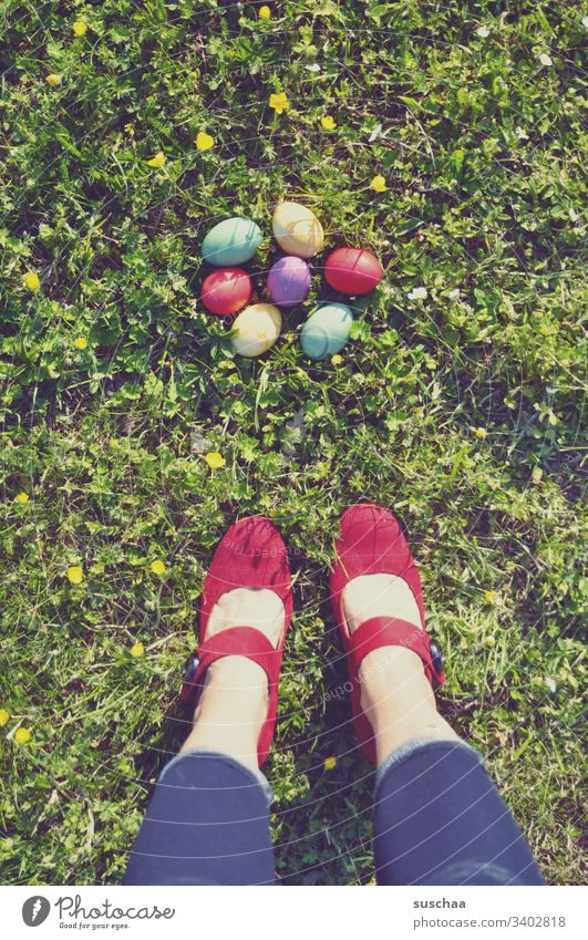 woman stands on the grass in front of colorful easter eggs Woman Stand Legs feet High heels Red variegated Easter Easter eggs colored Footwear colorful eggs