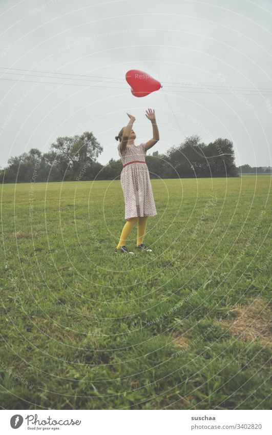 girl in a meadow playing with a heart-shaped red balloon Child Meadow Nature Grass Playing Balloon Red Heart-shaped Infancy Summer Retro Freedom Field Dress