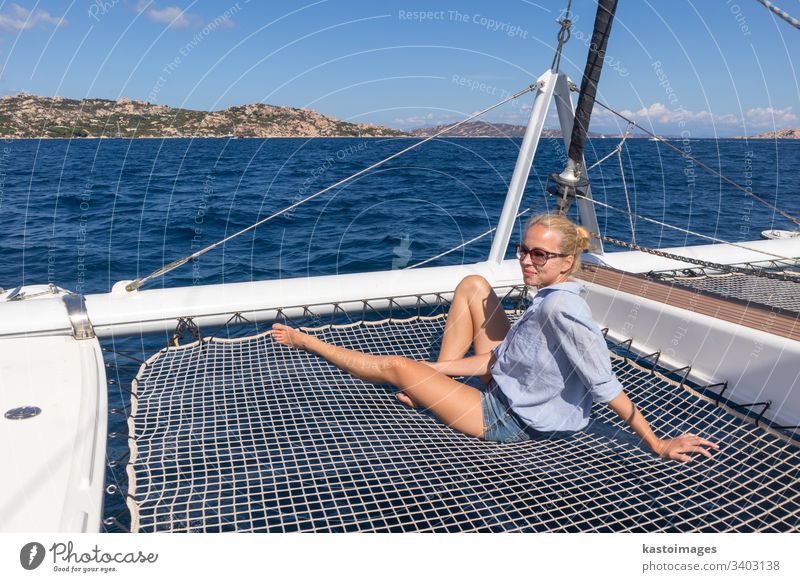 Woman relaxing on a summer sailin cruise, sitting on a luxury catamaran, sailing in Maddalena Archipelago, Sardinia, Italy. woman boat sea sailingboat nautic