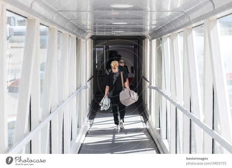 Female passenger carrying the hand luggage bag, walking the airplane boarding corridor. travel aircraft woman transfer transport traveller holiday airport