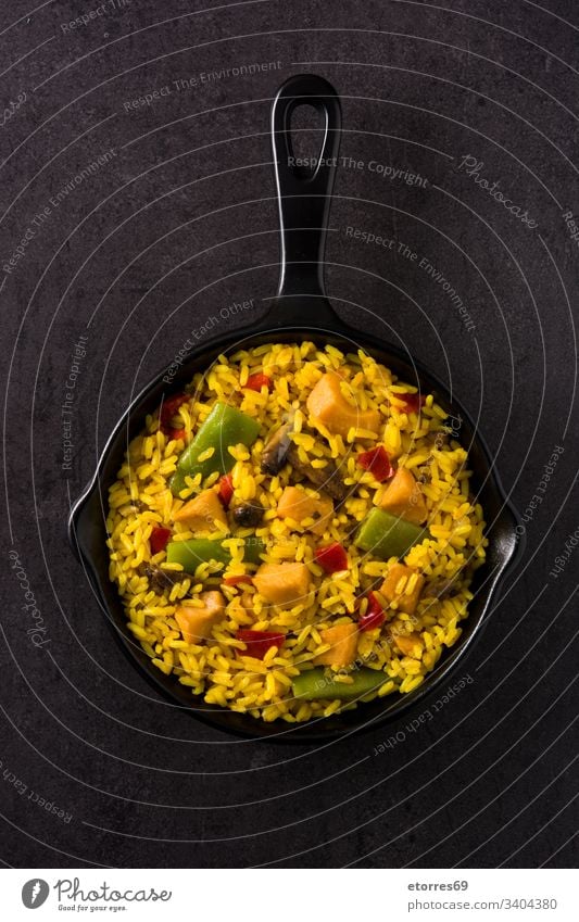 Fried rice with chicken and vegetables in frying pan on black background top view asian chinese cooked cuisine delicious dish food fried grain green meat