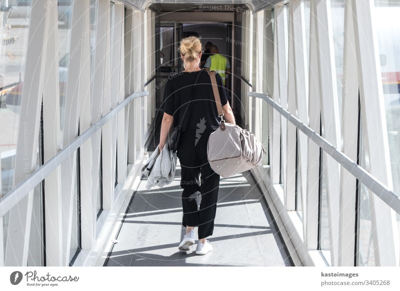 Female passenger carrying the hand luggage bag, walking the airplane boarding corridor. travel aircraft woman transfer transport traveller holiday airport