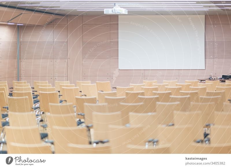 Empty wooden seats in a cotmporary lecture hall. auditorium education empty conference meeting presentation room chairs school white screen study university