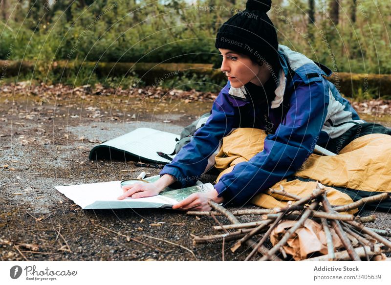 Focused young female hiker orientating on map in camp orientate woman backpacker search location trekking autumn navigate traveler check countryside equipment