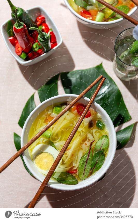 Oriental noodles soup in a restaurant food ramen asian chinese white vegan food vegetables vegetarian healthy food egg carrots onion spinach shiitake background